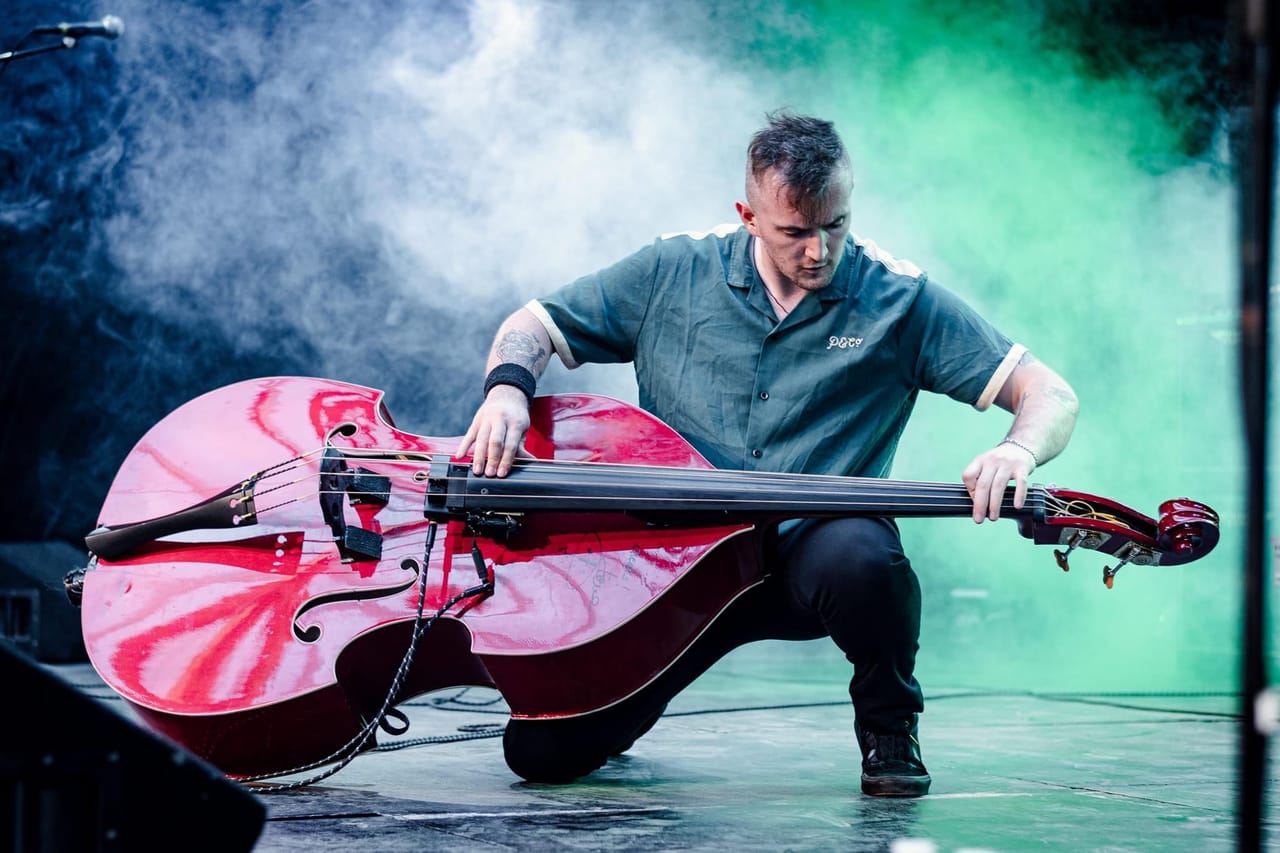 Scott McParland playing Double Bass in a showman style on it's side with atmospheric smoke and stage lighting